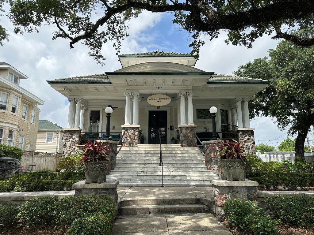 Canal Street Inn exterior — Greek Revival mansion with white columns, stone porch, and gardens