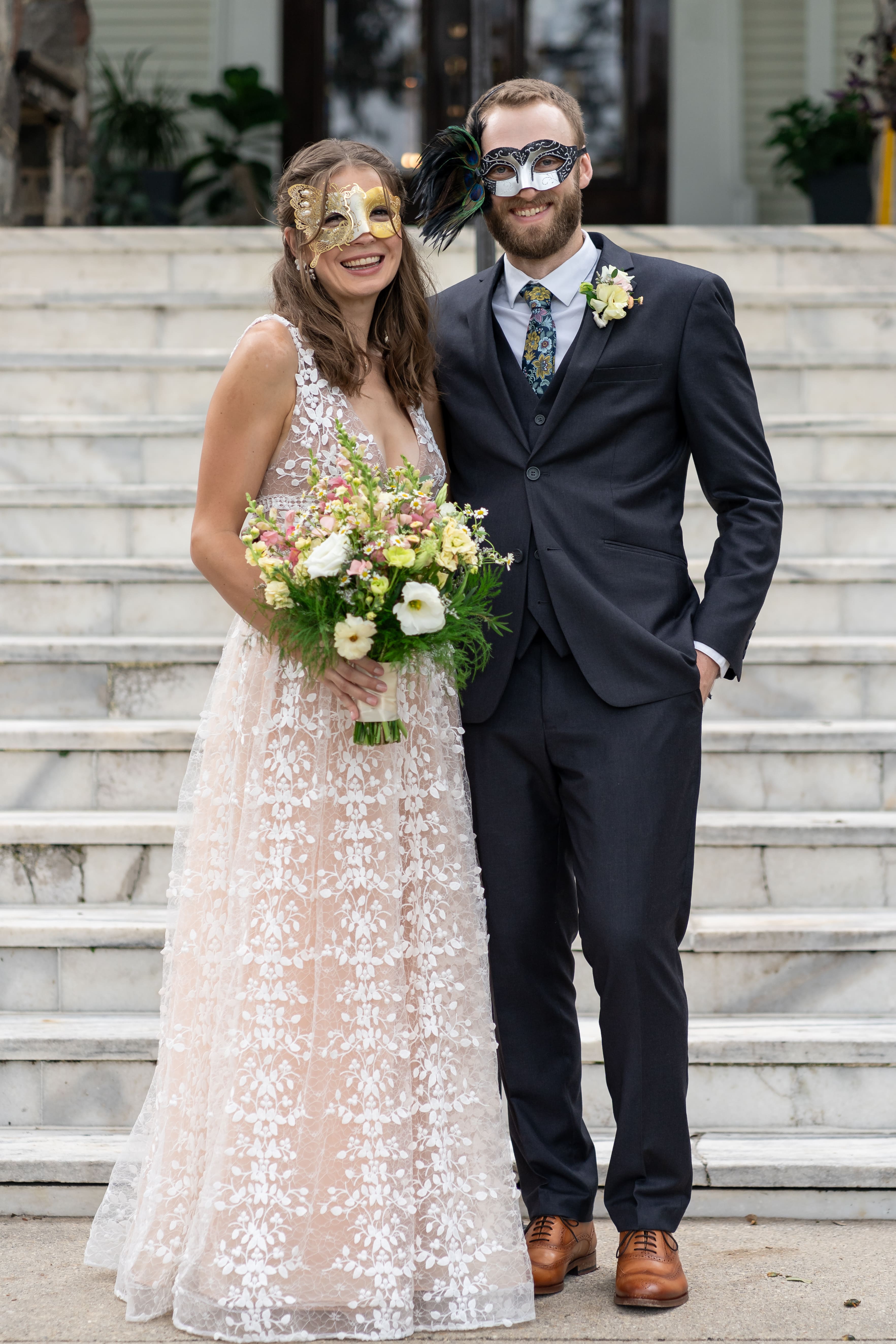 Couple in formal attire with masquerade masks on the steps of Canal Street Inn