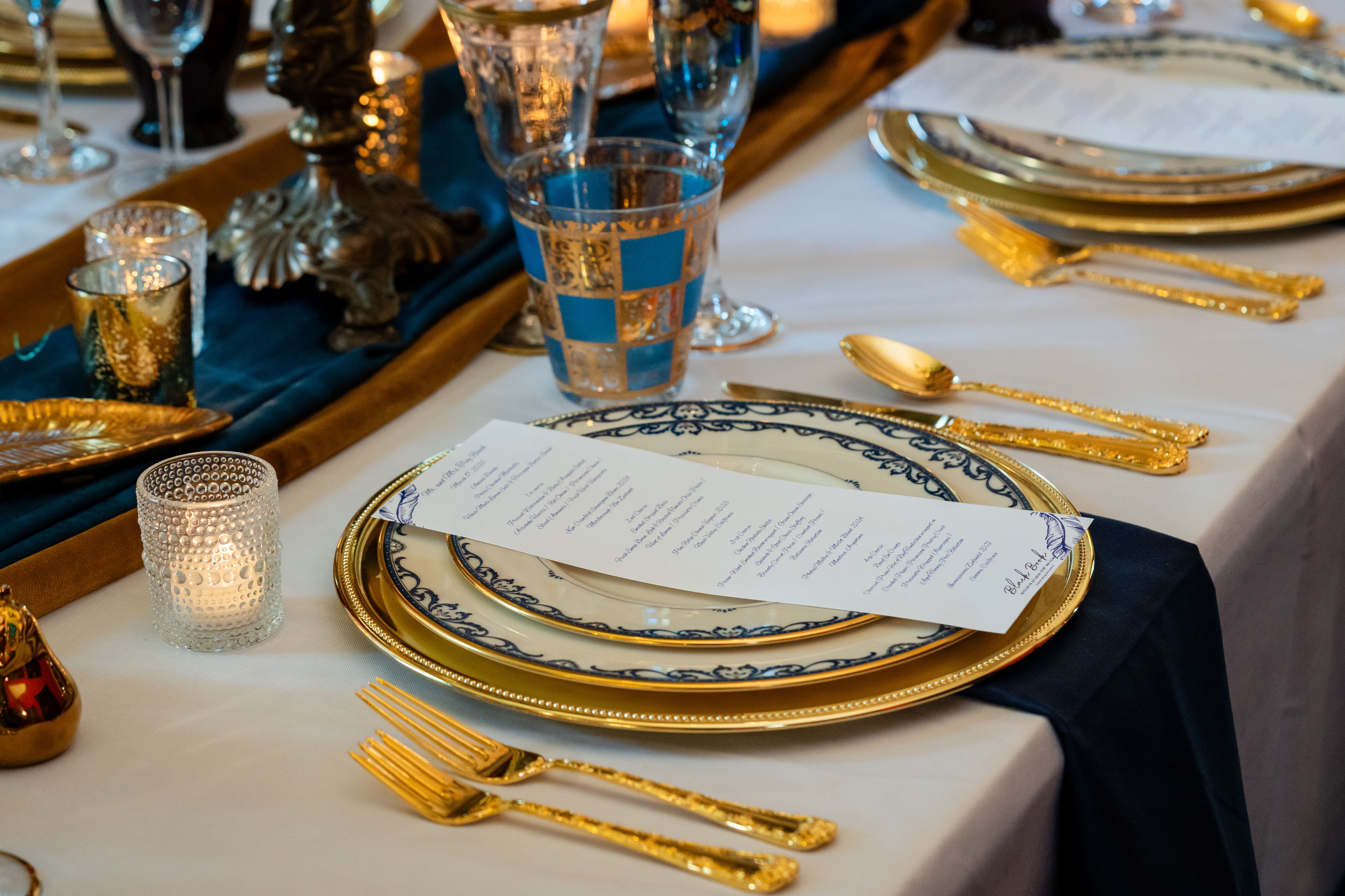 Close-up of a formal parlor place setting with gold flatware and blue-and-gold glassware at Canal Street Inn