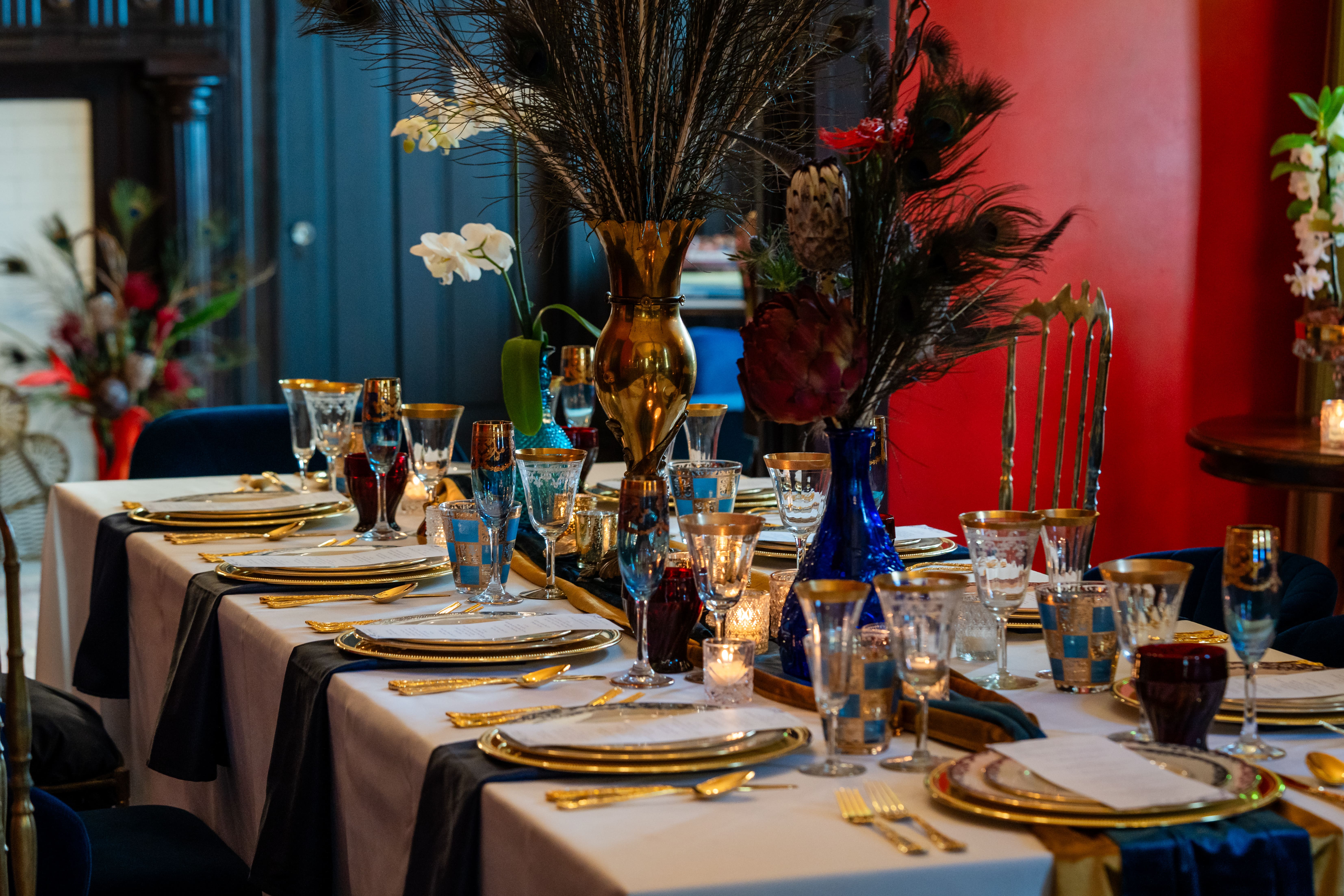 Long parlor dining table with peacock feather centerpieces and gold accents inside Canal Street Inn