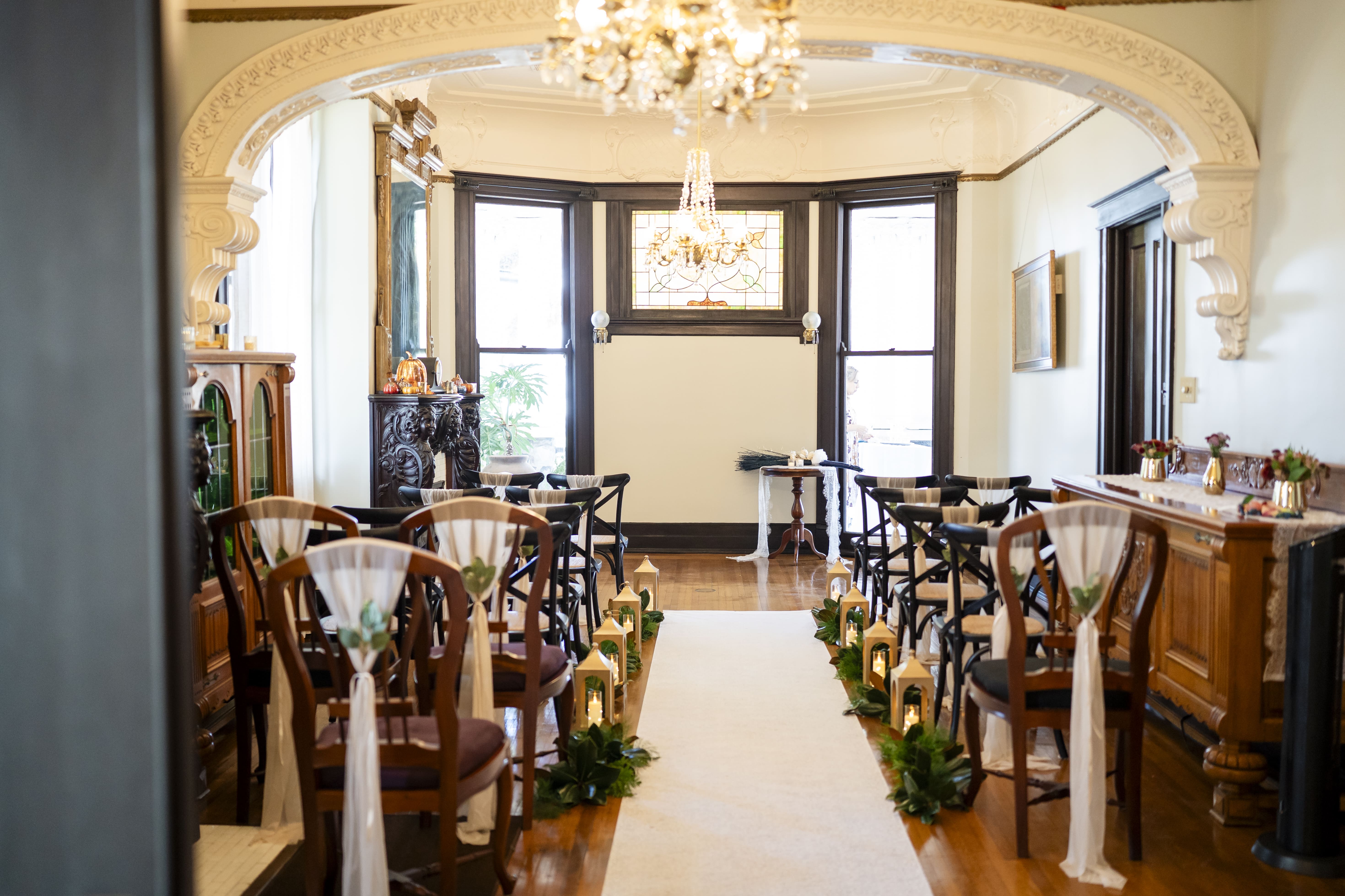 Victorian parlor ceremony aisle with lanterns and stained glass at Canal Street Inn
