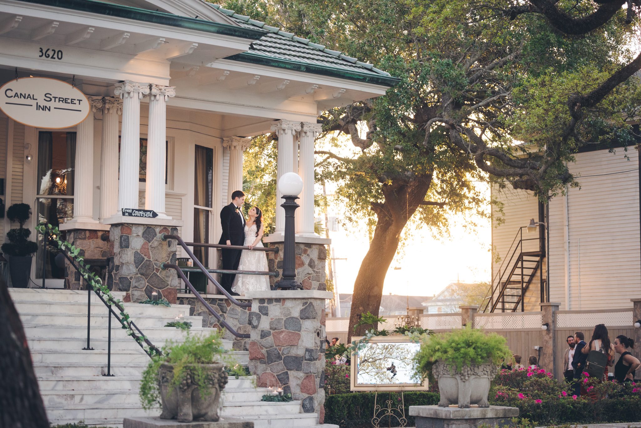 Savannah and Patrick standing together on the steps of Canal Street Inn beneath its historic oak trees.
