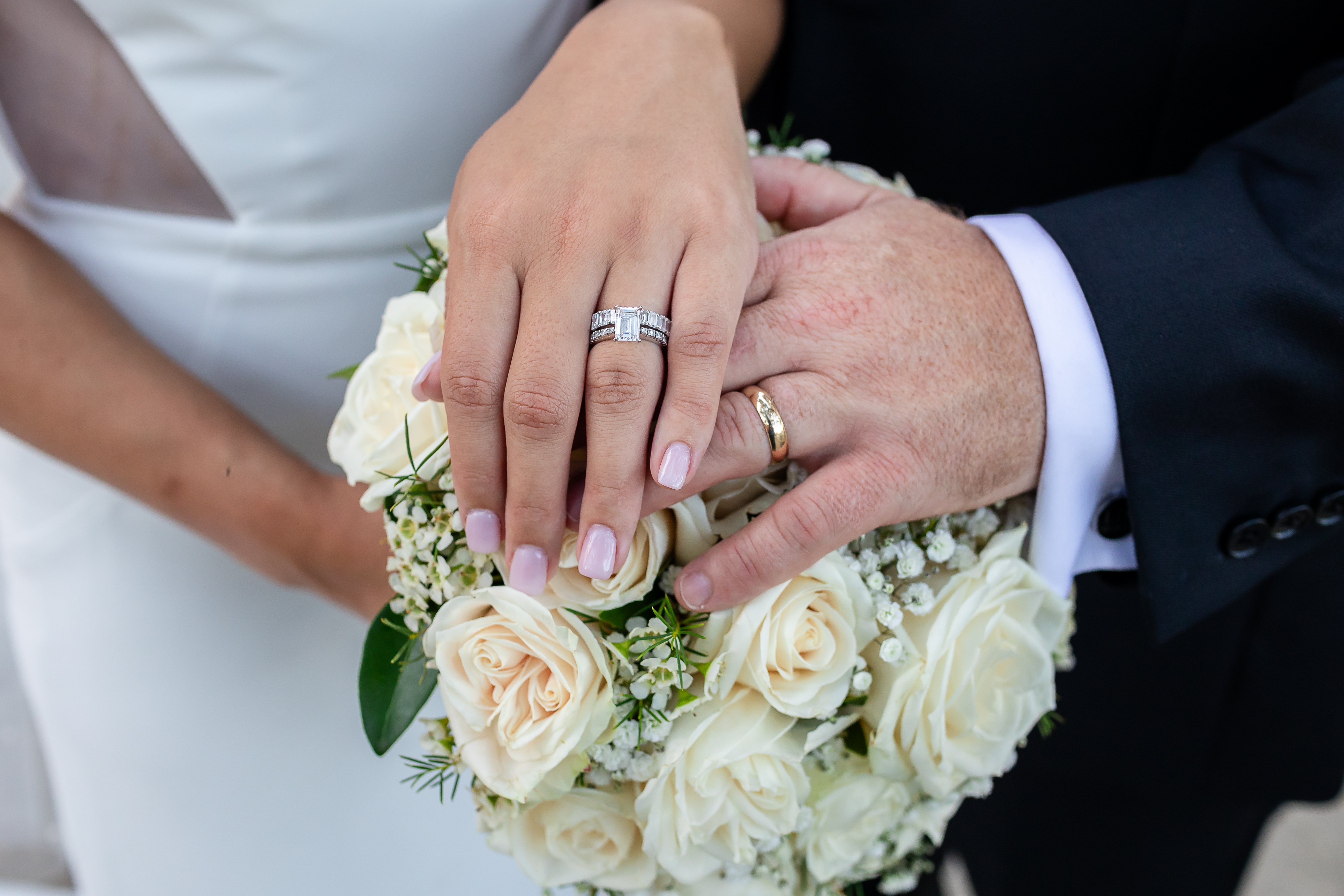Bride and groom holding hands over a white rose bouquet — Intimate Elopements at Canal Street Inn